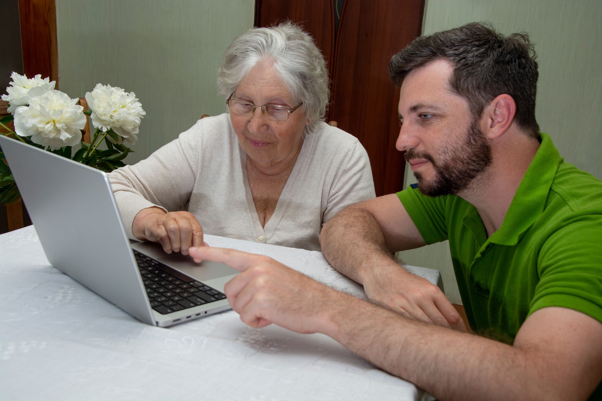 Elderly senior woman learning to use a laptop computer from teen male grandson